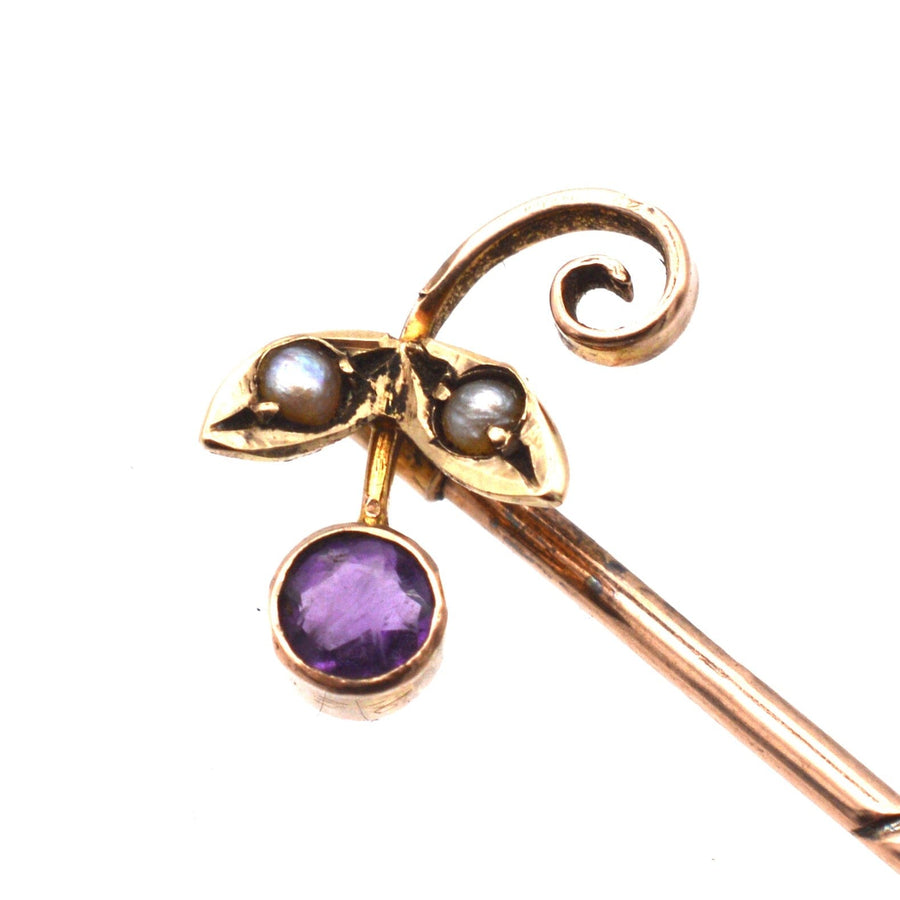 Edwardian 9ct gold tie pin featuring amethyst and seed pearl flower design, includes stoppers for secure wear.