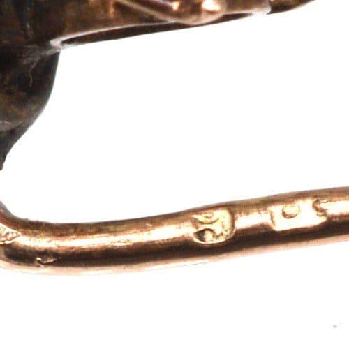 Close-up of an Edwardian 9ct gold bee tie pin showcasing opal, seed pearl, and garnet details.