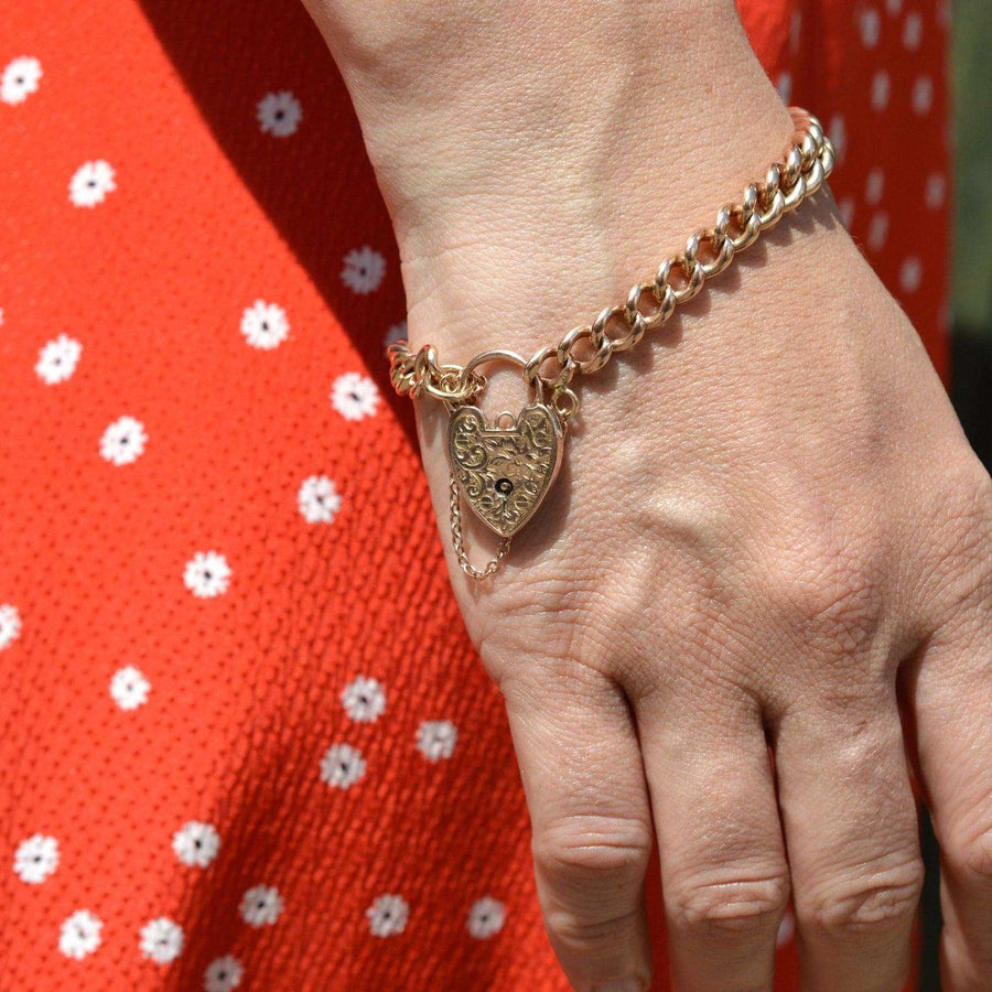 Edwardian 9ct gold curb link bracelet with heart padlock, showcasing intricate design and solid craftsmanship.