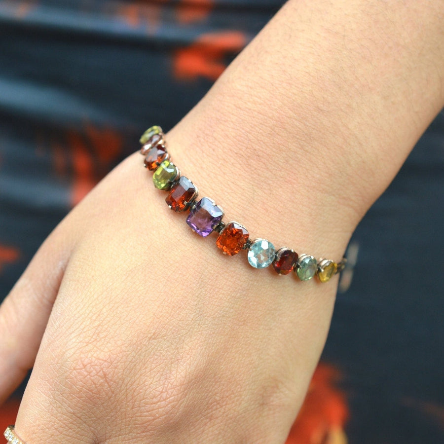 Edwardian 9ct gold harlequin multi-gem bracelet featuring citrine, garnet, aquamarine, and more on a wrist.