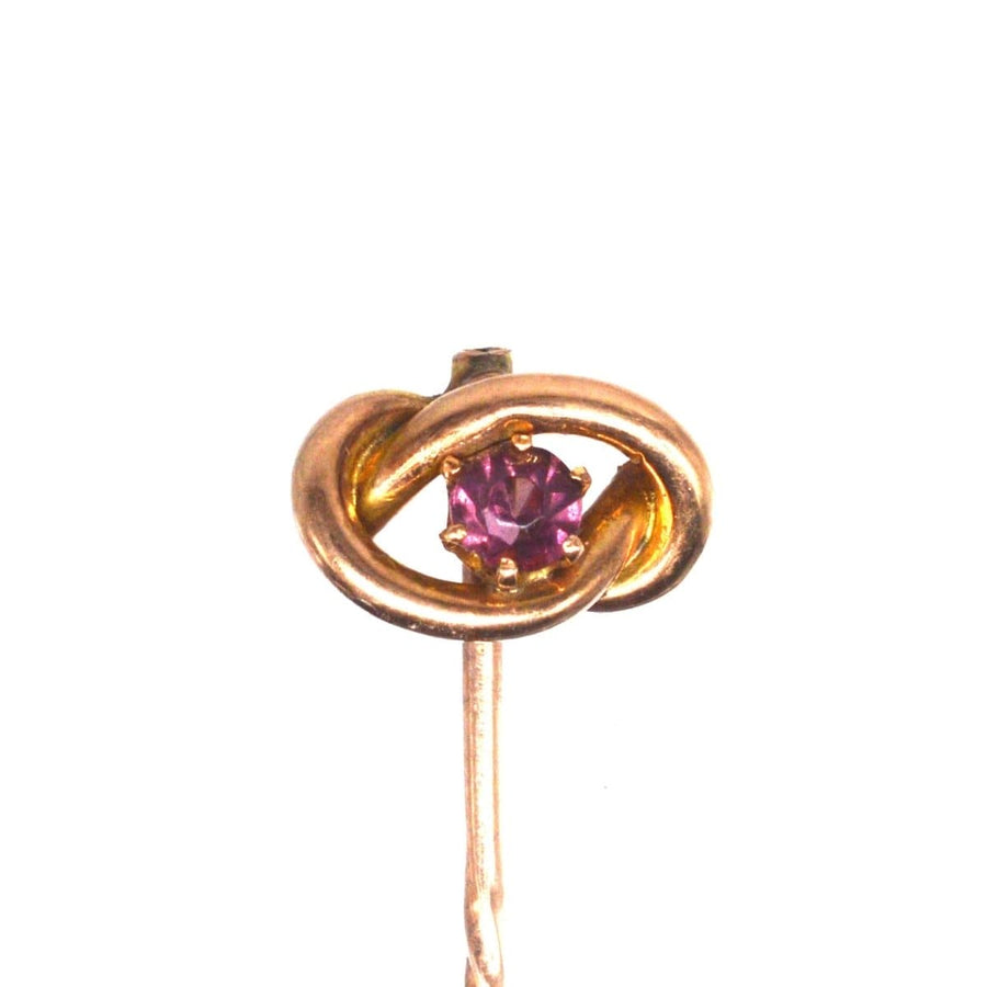 Edwardian 9ct gold lover's knot tie pin featuring a vibrant garnet centerpiece, symbolizing infinite love.