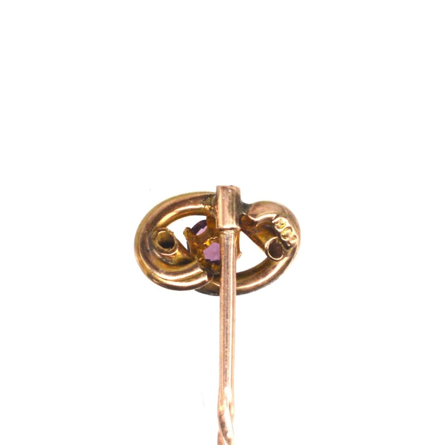 Edwardian 9ct gold lover's knot tie pin with a vibrant garnet centerpiece.