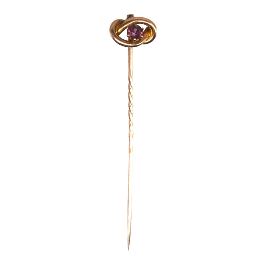 Edwardian 9ct gold lover's knot tie pin featuring a vibrant garnet gemstone, symbolizing love and connection.