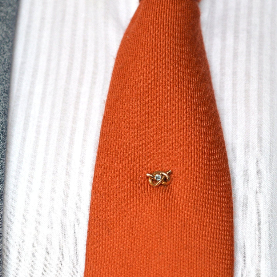 9ct gold lover's knot tie pin with aquamarine on an orange silk tie, showcasing Edwardian era elegance.
