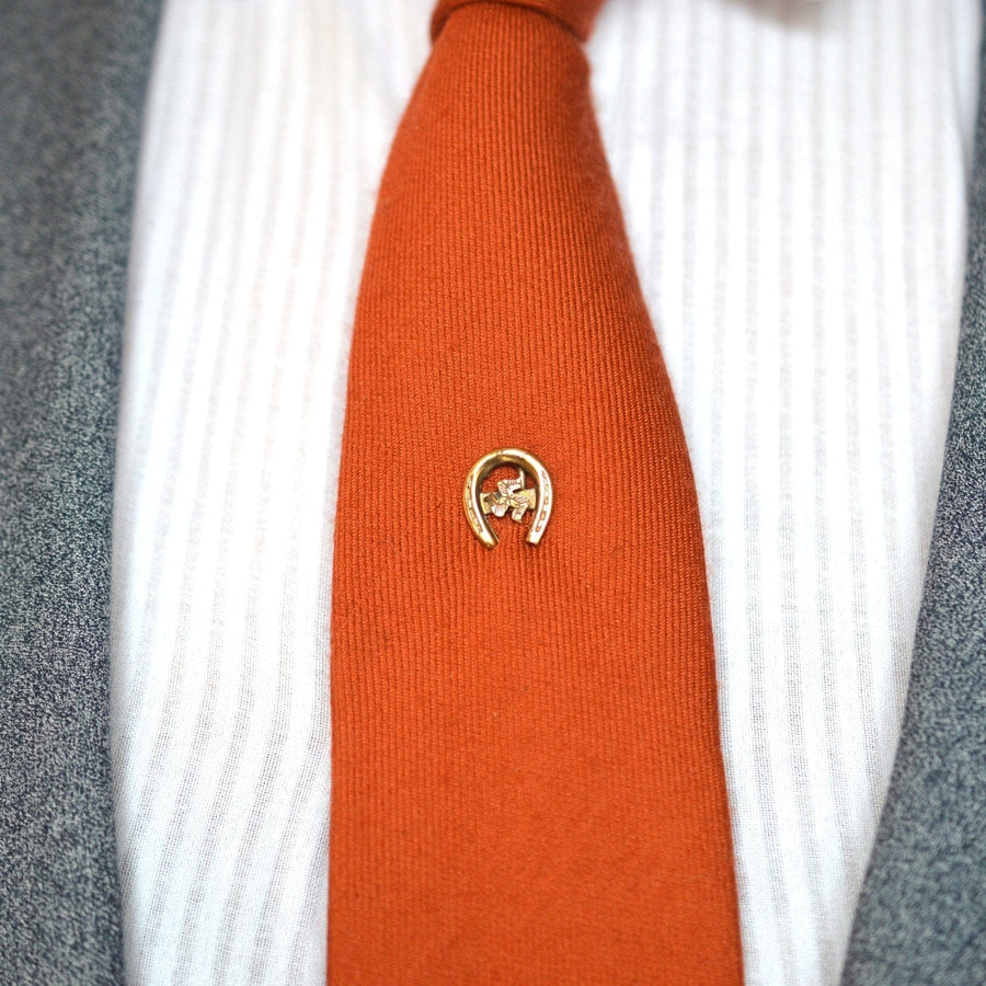 Edwardian 9ct gold lucky horseshoe tie pin with Isle of Man Triskelion on an orange tie.