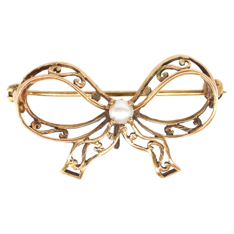 Edwardian 9ct gold brooch featuring a pearl and intricate bow design, perfect for lapel wear.