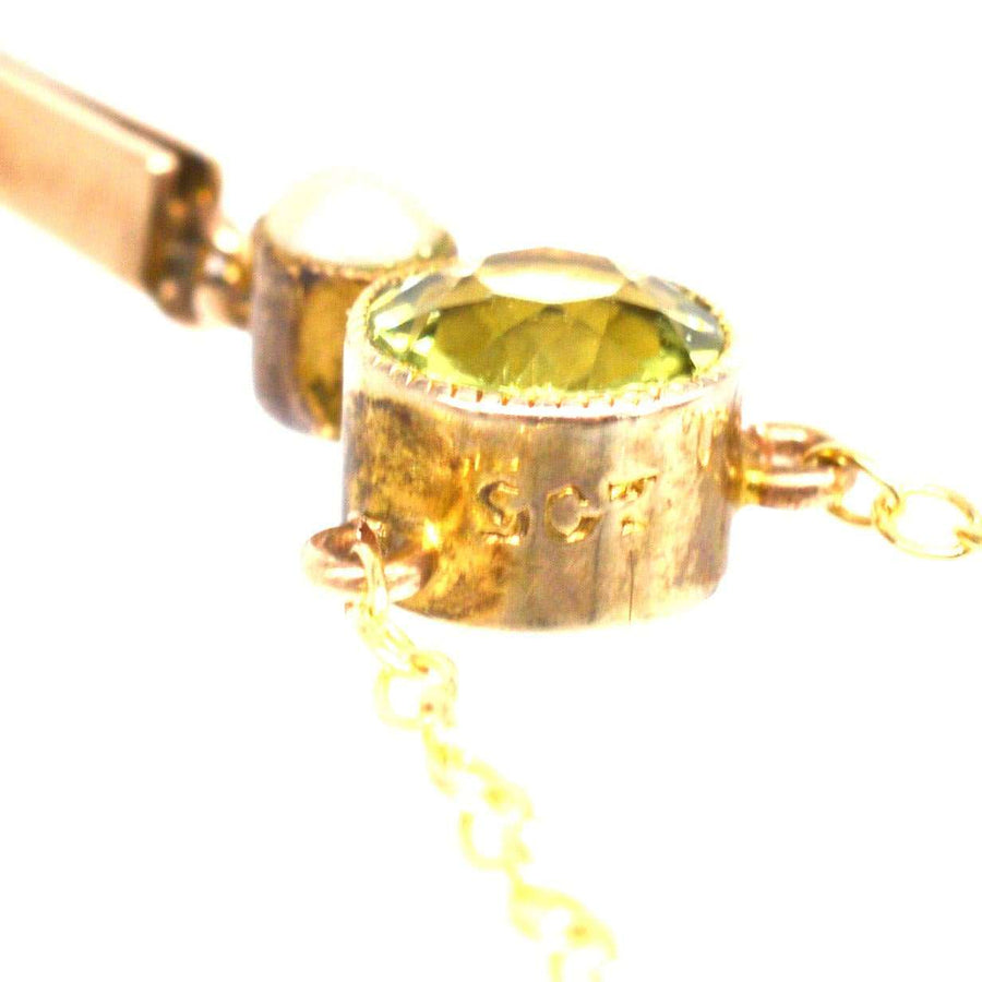 Close-up of Edwardian 9ct gold pendant featuring a vibrant olive green peridot gemstone and a pearl.