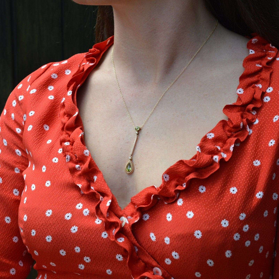 Stylish woman wearing Edwardian 9ct gold peridot and pearl drop pendant on a delicate chain.