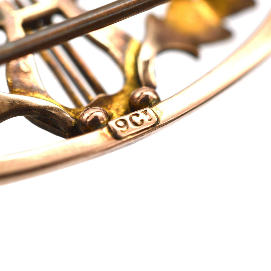 Close-up of 9ct gold antique lyre bar brooch showing hallmark and intricate scroll details.