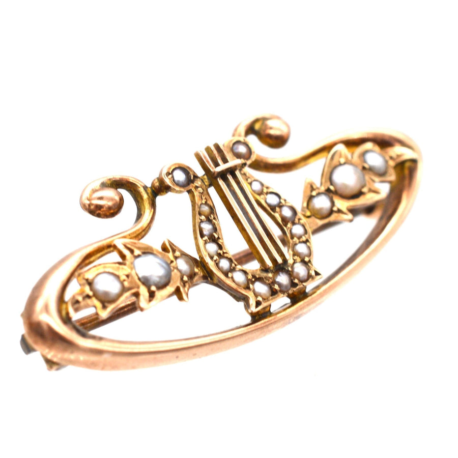 Edwardian 9ct gold bar brooch featuring a lyre design with split pearls and intricate scroll details.