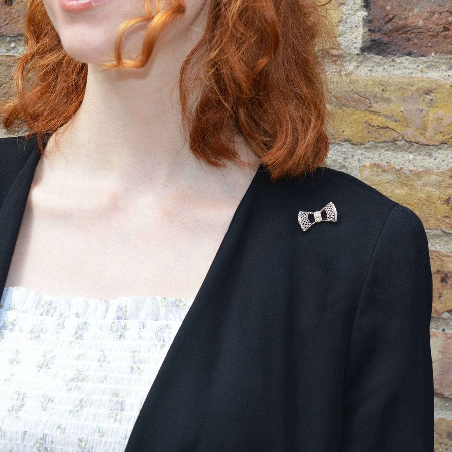 Model wearing Edwardian 'Belle Epoque' 18ct gold and platinum bow brooch on black blazer, showcasing elegant design.