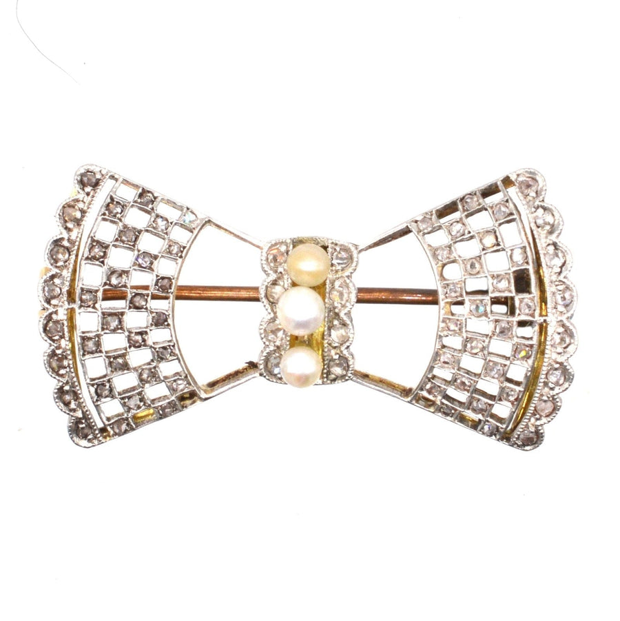 Edwardian 18ct gold and platinum bow brooch adorned with diamonds and pearls, showcasing intricate lace design.