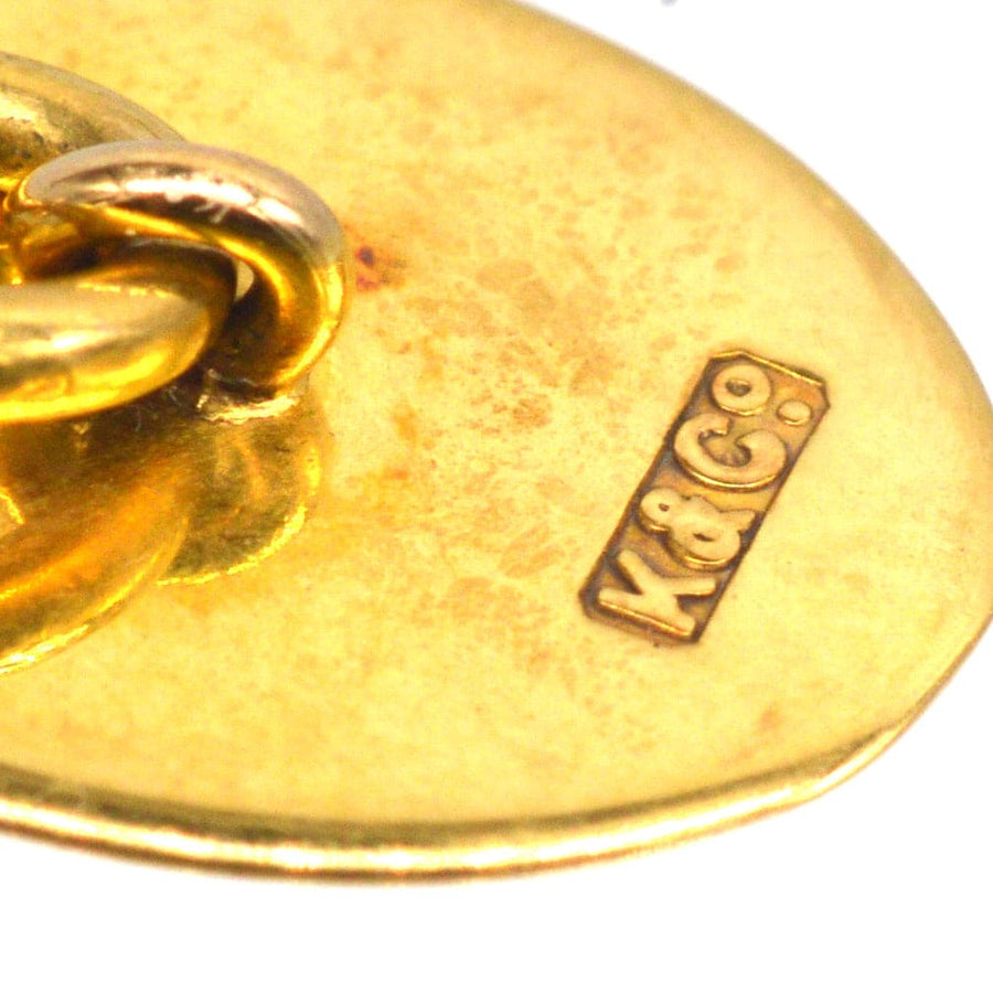 Close-up of vintage gold cufflinks with K & G hallmark, showcasing intricate design details.