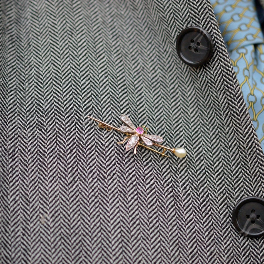 Elegant Edwardian bug brooch with pink sapphire, emeralds, diamonds, and natural pearl on a suit lapel.