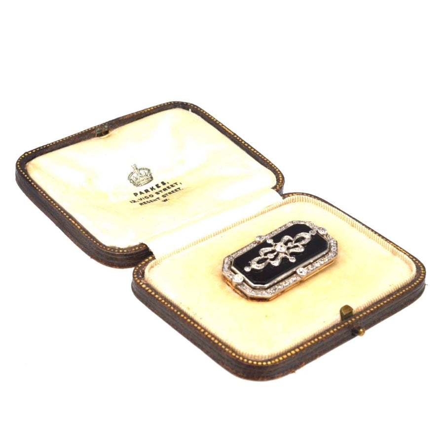 Edwardian platinum and gold brooch featuring diamonds and onyx, presented in a vintage jeweller's box.