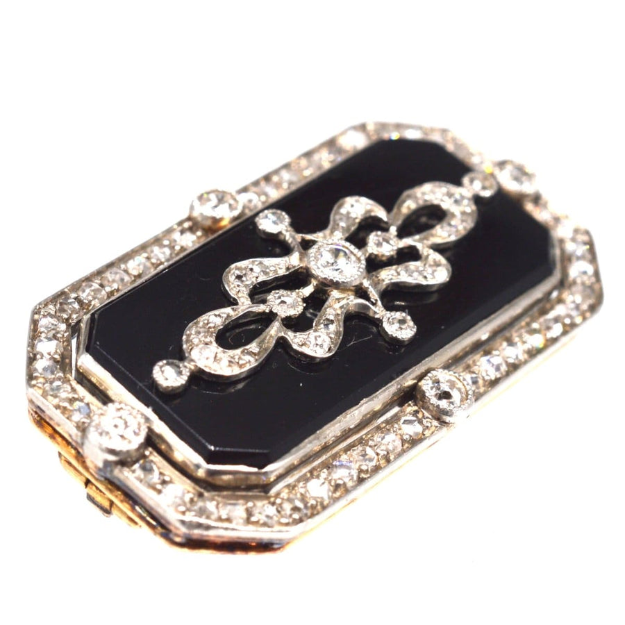 Edwardian brooch in platinum, gold, onyx, decorated with intricate diamond design, perfect for antique jewelry collections.