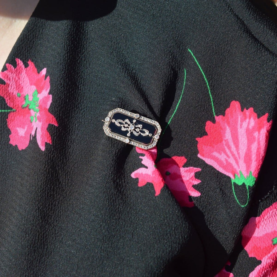Edwardian platinum and gold brooch with onyx and diamond detail on floral blouse.