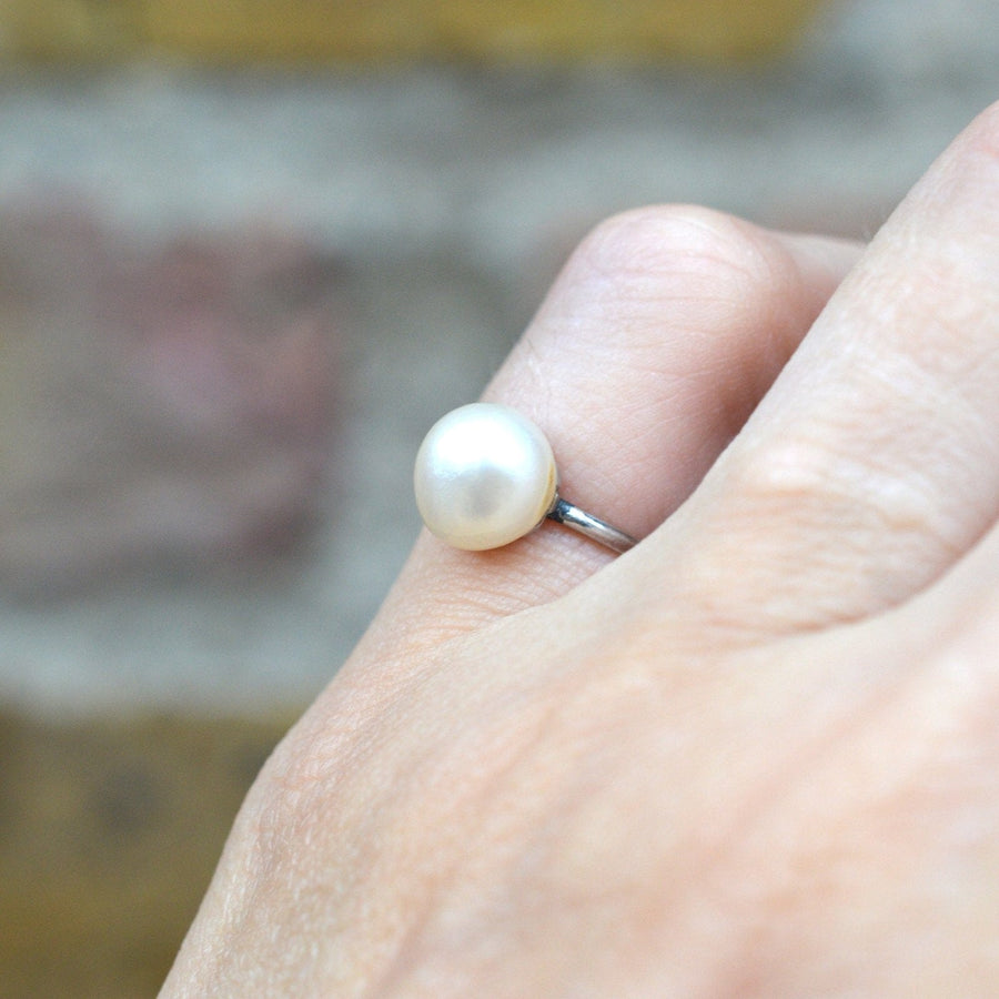 Edwardian platinum ring featuring a lustrous natural saltwater pearl, circa 1910s, elegantly worn on a hand.