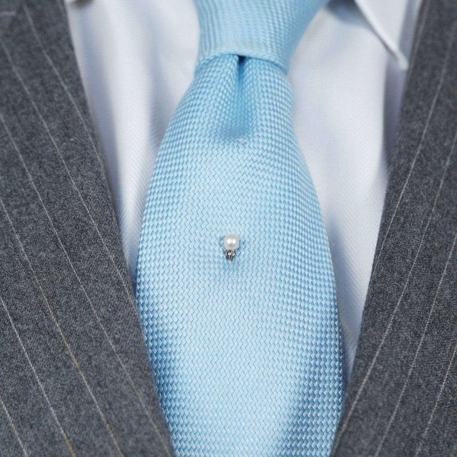 Edwardian silver and gold tie pin with natural pearl accent on a light blue silk tie.