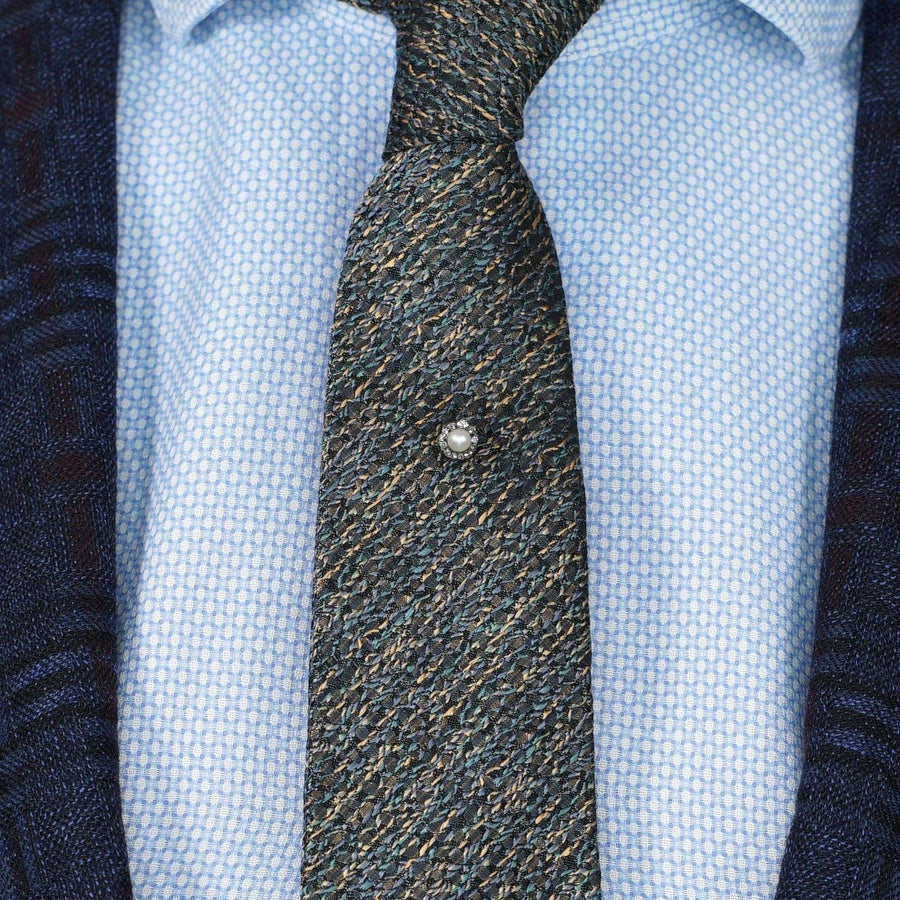 Edwardian silver and gold tie pin with natural pearl on a textured tie and dress shirt.