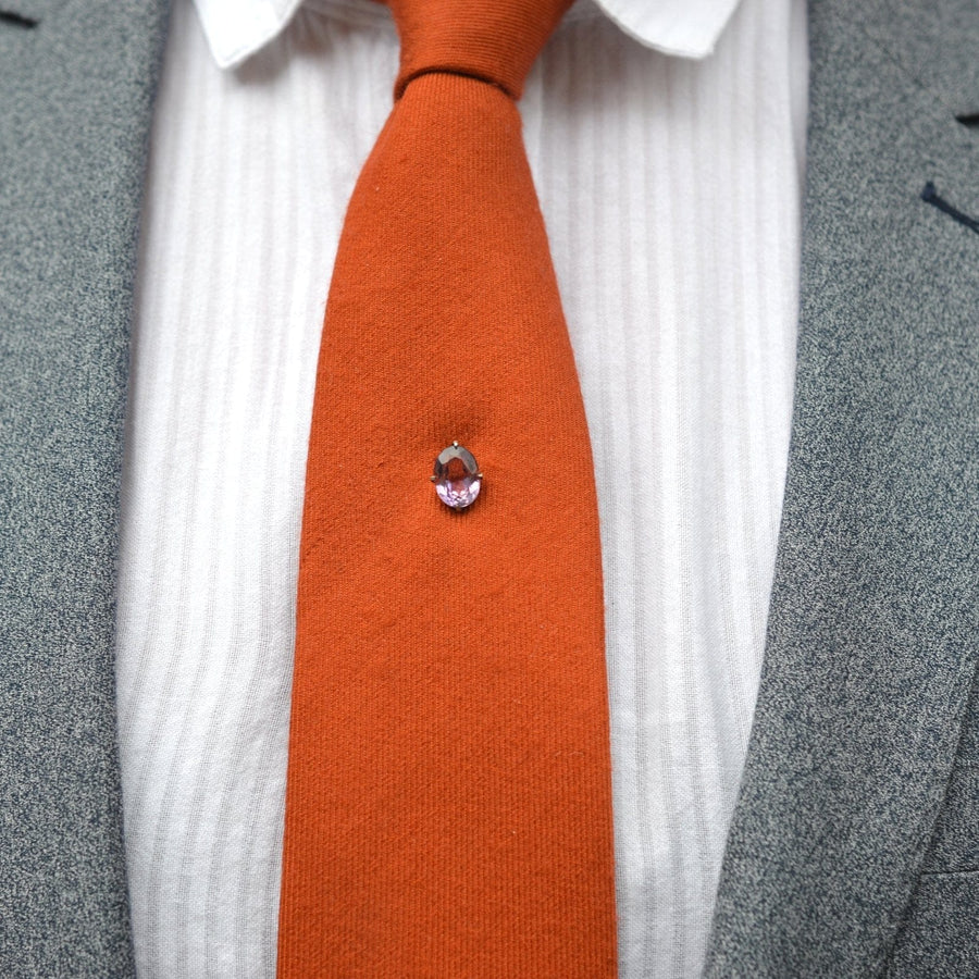 Edwardian silver and amethyst tie pin on an orange tie, showcasing timeless elegance and style.
