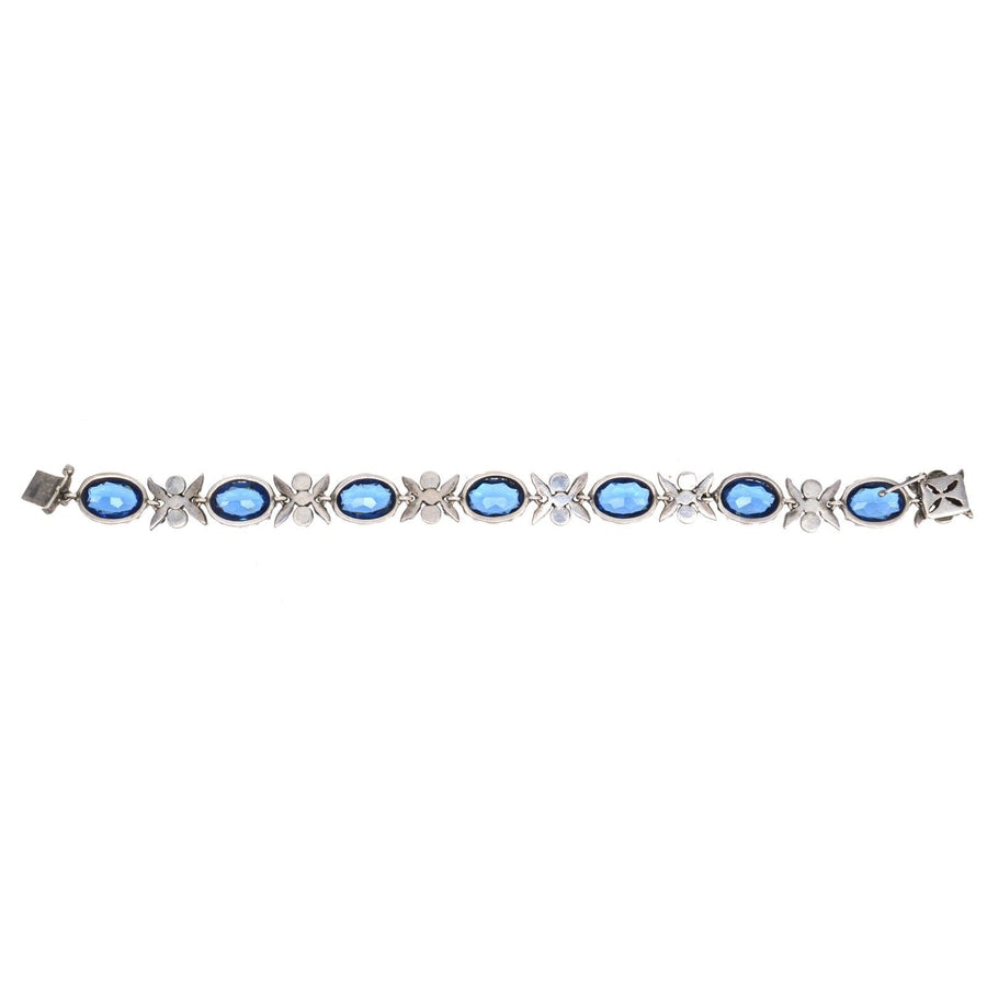 Edwardian silver bracelet featuring sapphire blue and white paste stones set in floral designs.