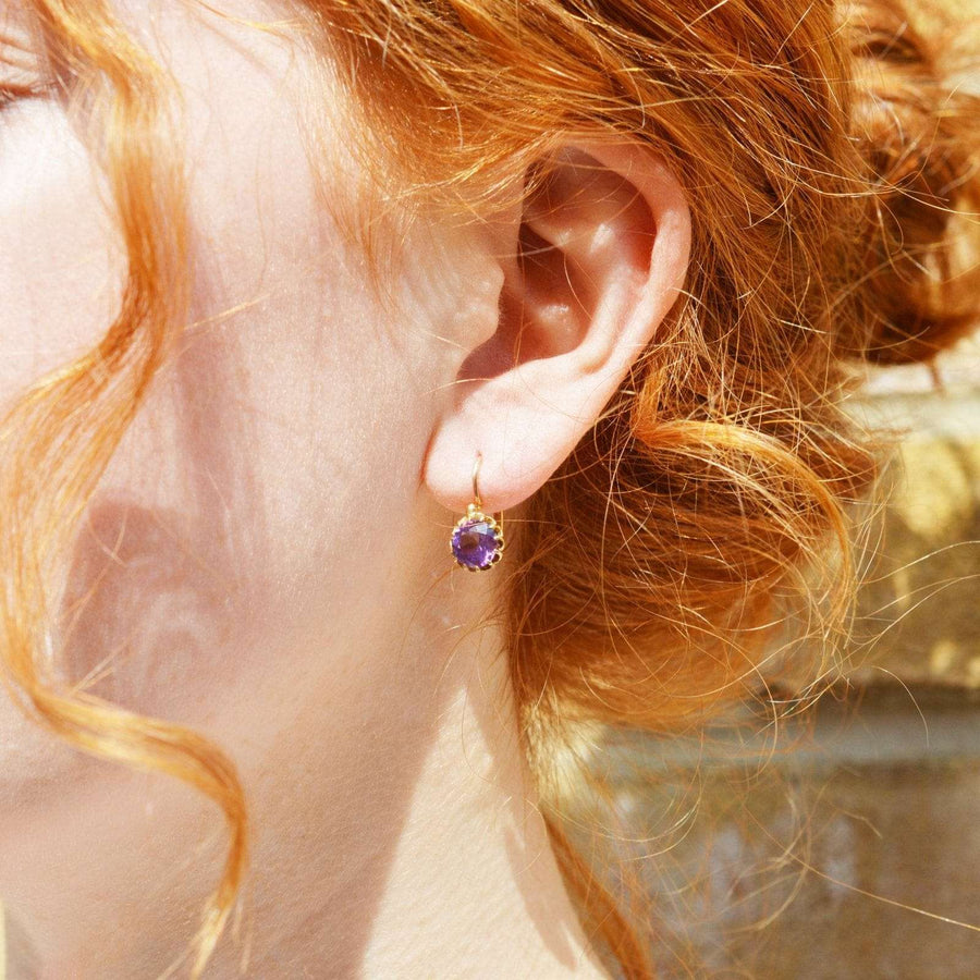 Close-up of a woman's ear featuring a vintage 19th century gold earring with purple amethyst.
