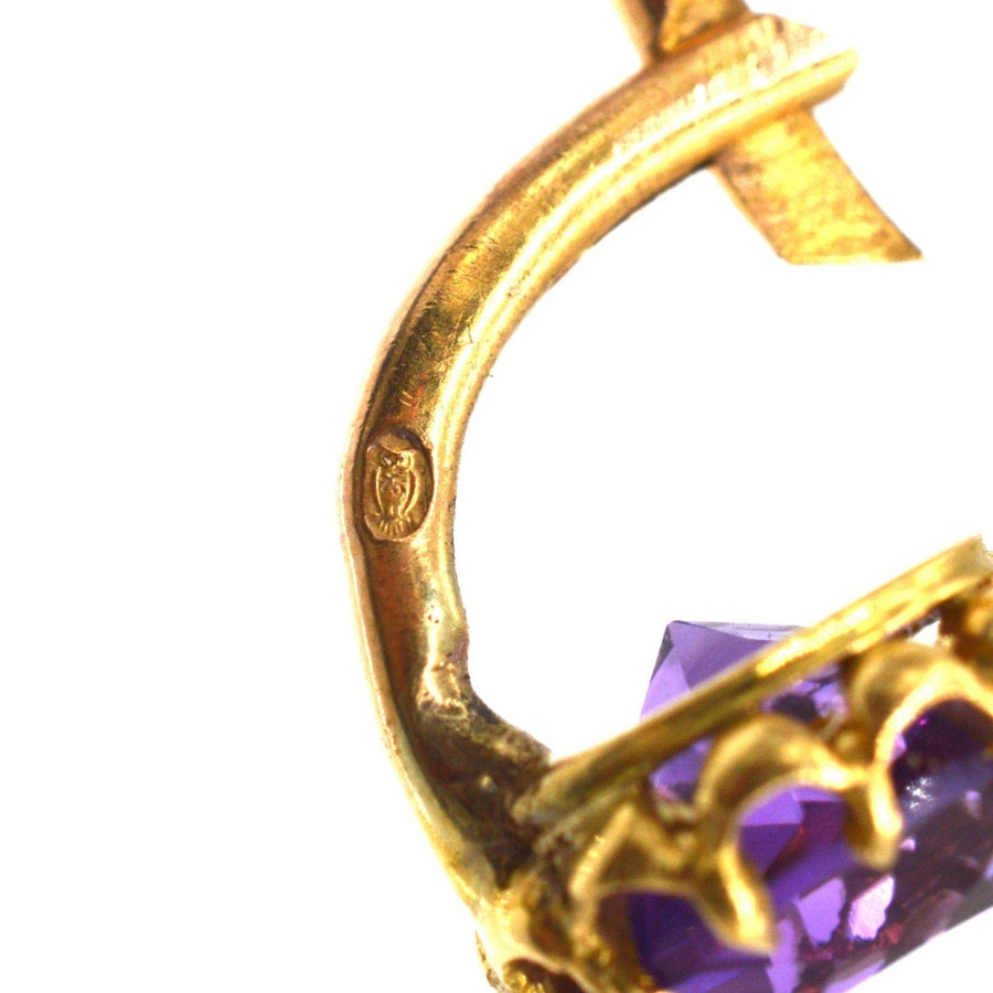 Close-up of 19th century gold earring with amethyst, showcasing intricate design and hallmark detail.