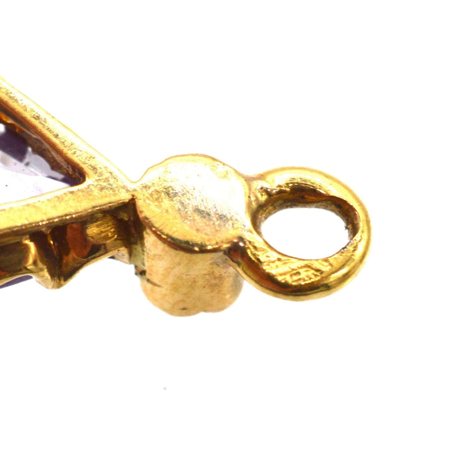 Close-up of vintage gold earring setting showcasing amethyst and pearl details, highlighting intricate craftsmanship.