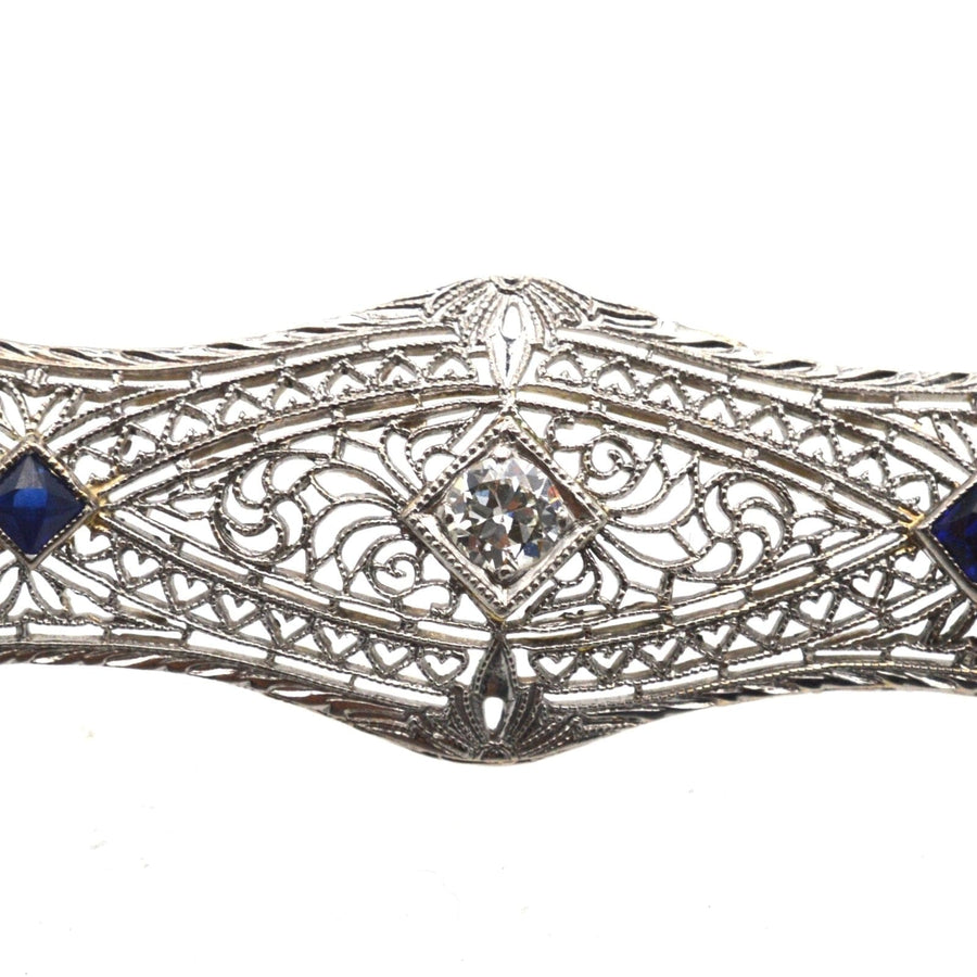 Elegant French Art Deco 14ct gold bar brooch featuring sapphires and a diamond, set in intricate white gold tracery.