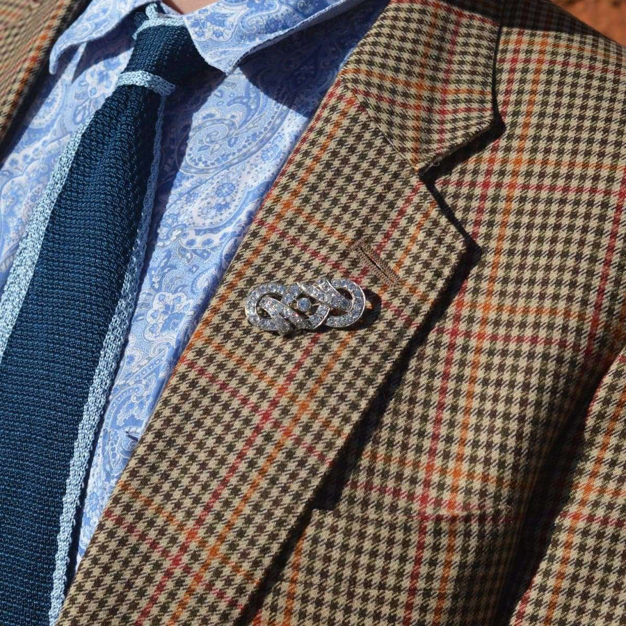 French Art Deco silver paste brooch displayed on a checked blazer lapel, exemplifying elegant 1930s-1940s design.