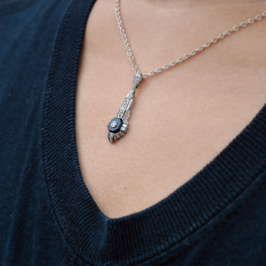 German Art Deco 18ct white gold pendant featuring onyx and diamond, showcasing intricate engraving and architectural design.