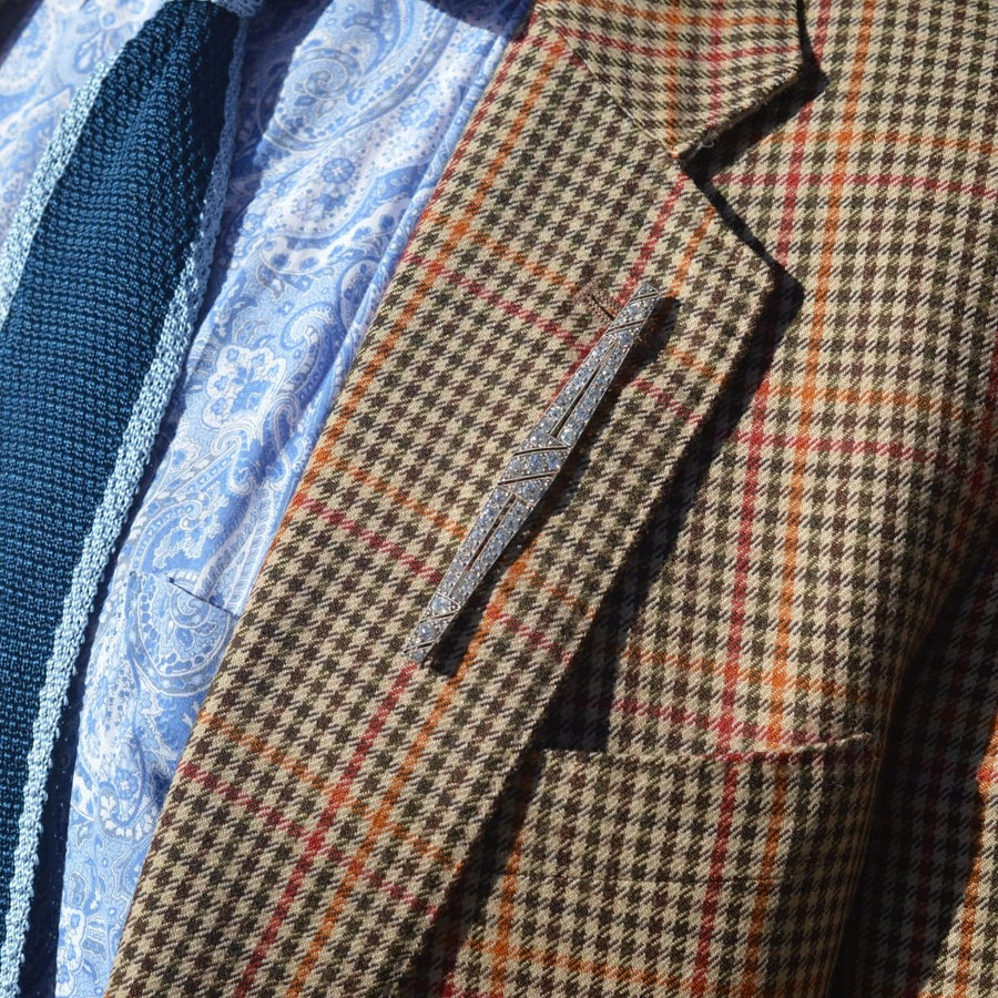 Large Art Deco diamond bar brooch showcased on a patterned blazer with a light blue shirt and tie.