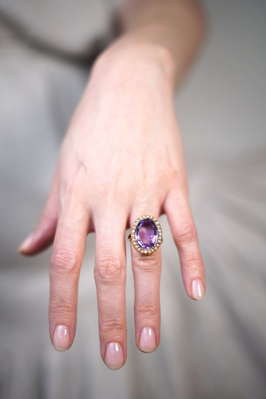 Large Edwardian 15ct gold amethyst and pearl cocktail ring worn on a hand, showcasing its elegant design.