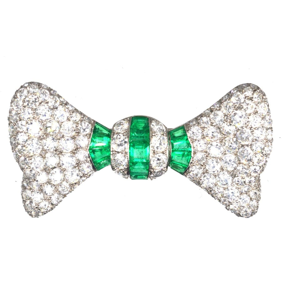 Art Deco vintage bow brooch featuring diamonds and emeralds in platinum setting.