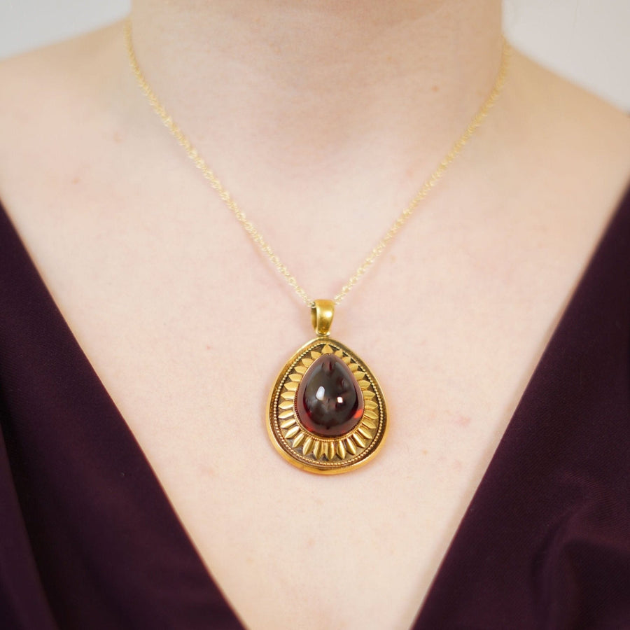 Large Victorian 15ct gold cabochon garnet pendant worn on a model, featuring intricate gold petals and beading.