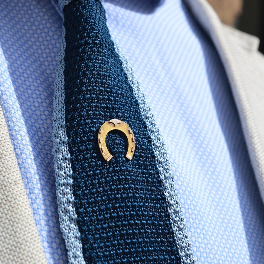 Large Victorian 9ct gold horseshoe tie pin on a textured blue tie, symbolizing good luck and classic elegance.