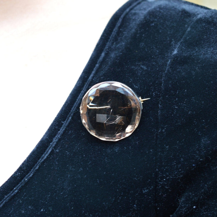 Large Victorian rutilated quartz brooch displayed on navy velvet fabric.