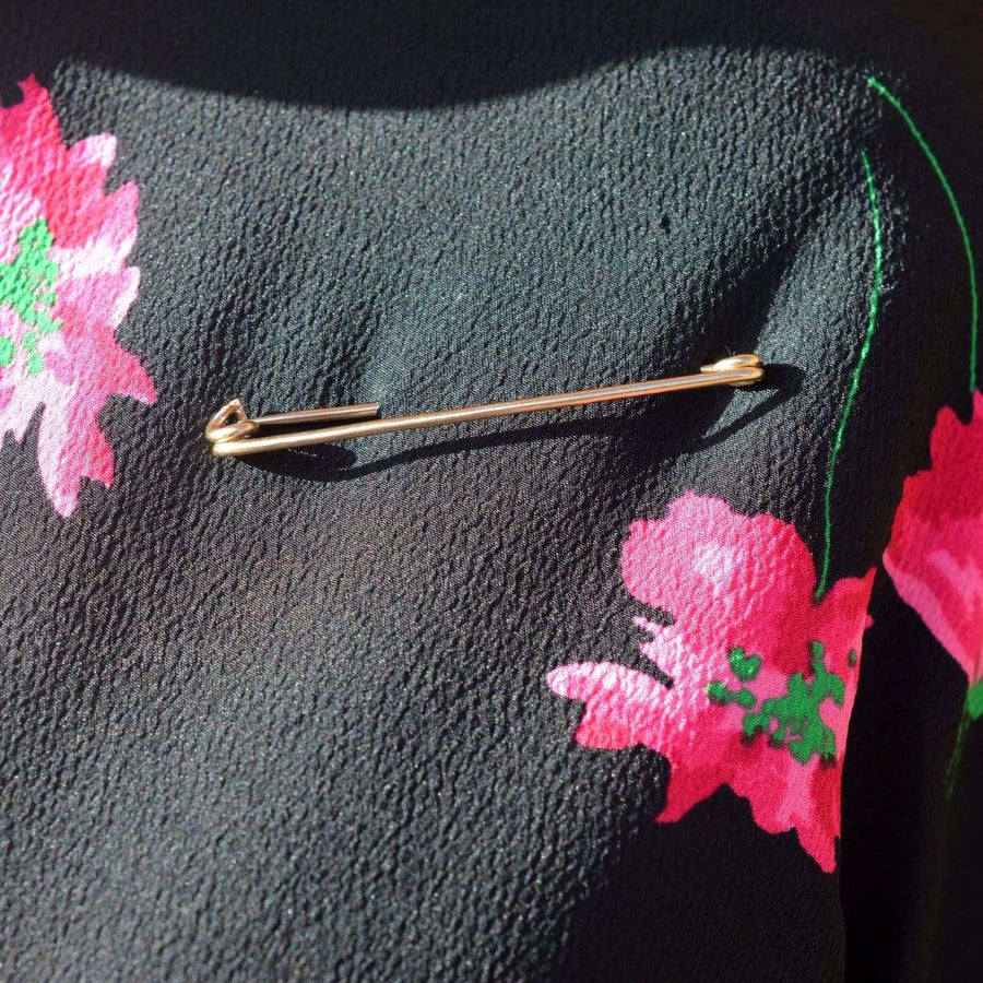 Large vintage 9ct gold safety pin brooch by Deakin & Francis on floral fabric.