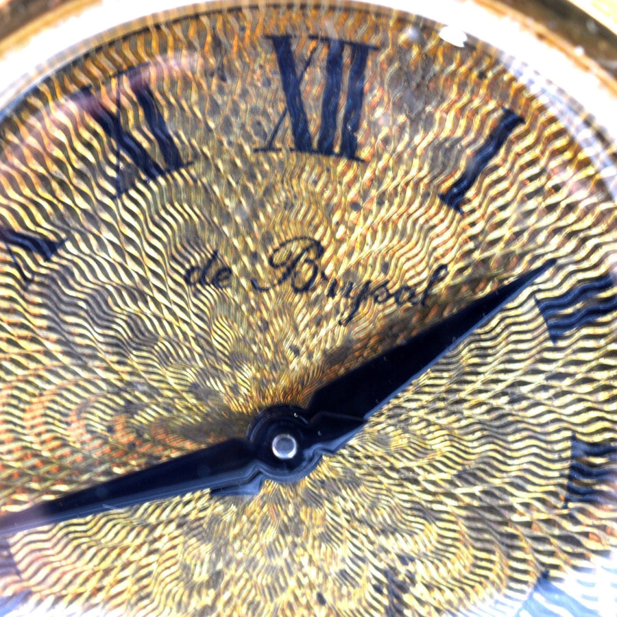 Close-up of de Brysal clock face, showcasing intricate gold design and blue hands.