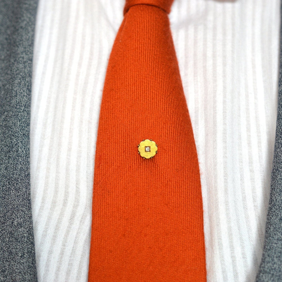 Elegant Late Victorian 15ct gold diamond flower tie pin on an orange silk tie.