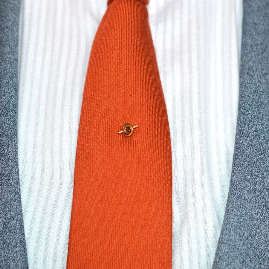 Late Victorian 9ct gold knot tie pin with garnet on an orange tie, showcasing a stylish vintage design from the 1890s.