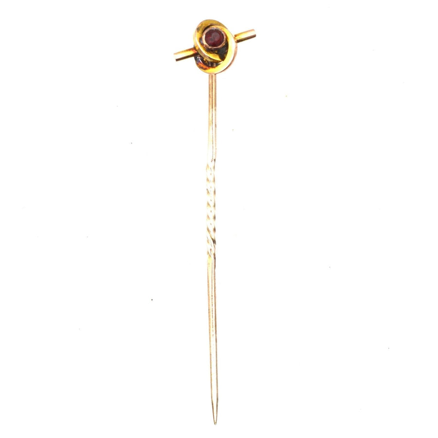 Victorian 9ct gold knot tie pin featuring a garnet, showcasing a stylish swirling design from the 1890s.