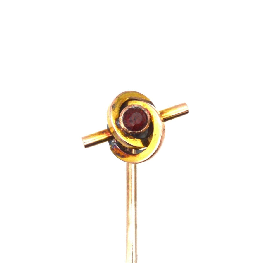 Late Victorian 9ct gold knot tie pin featuring a garnet, symbolizing unity and love, dating from the 1890s.