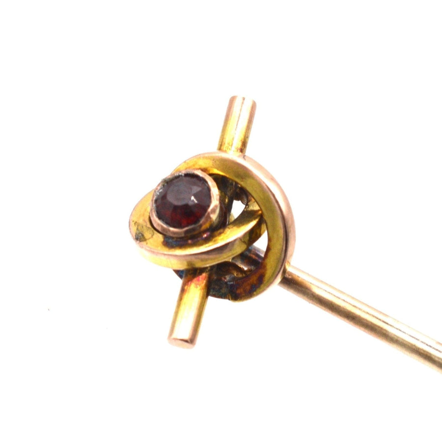 Late Victorian 9ct gold knot tie pin featuring a garnet, showcasing a swirling twist design.