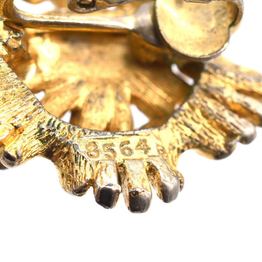 Close-up of Marcel Boucher 1960s gilt metal clip-on earrings, showcasing the signature and number 8564.