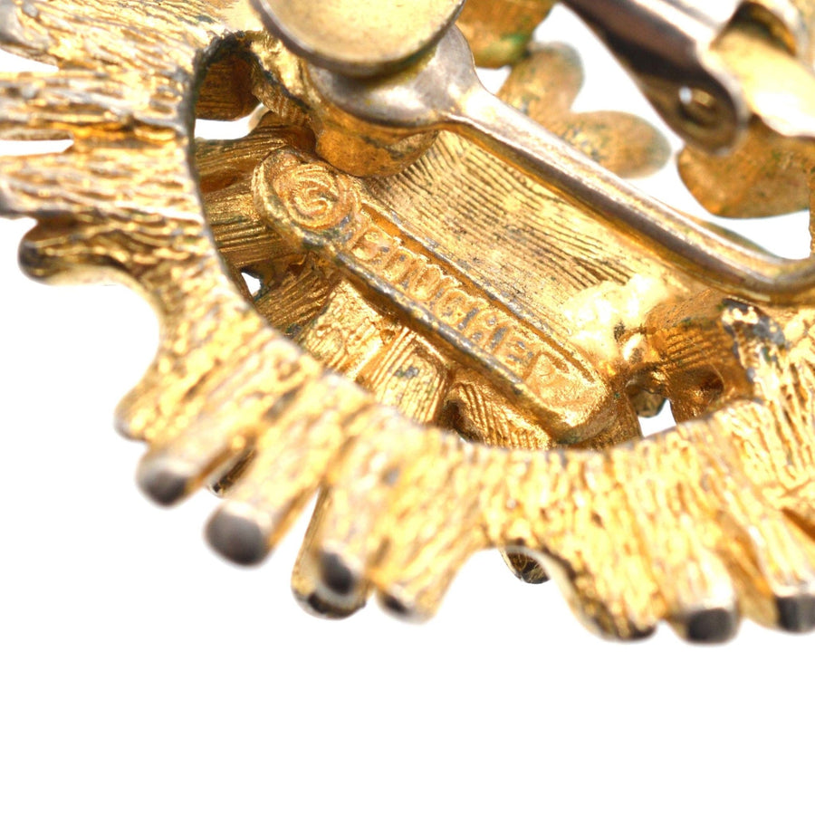 Close-up of Marcel Boucher 1960s gilt metal earrings, featuring signature and intricate design details.