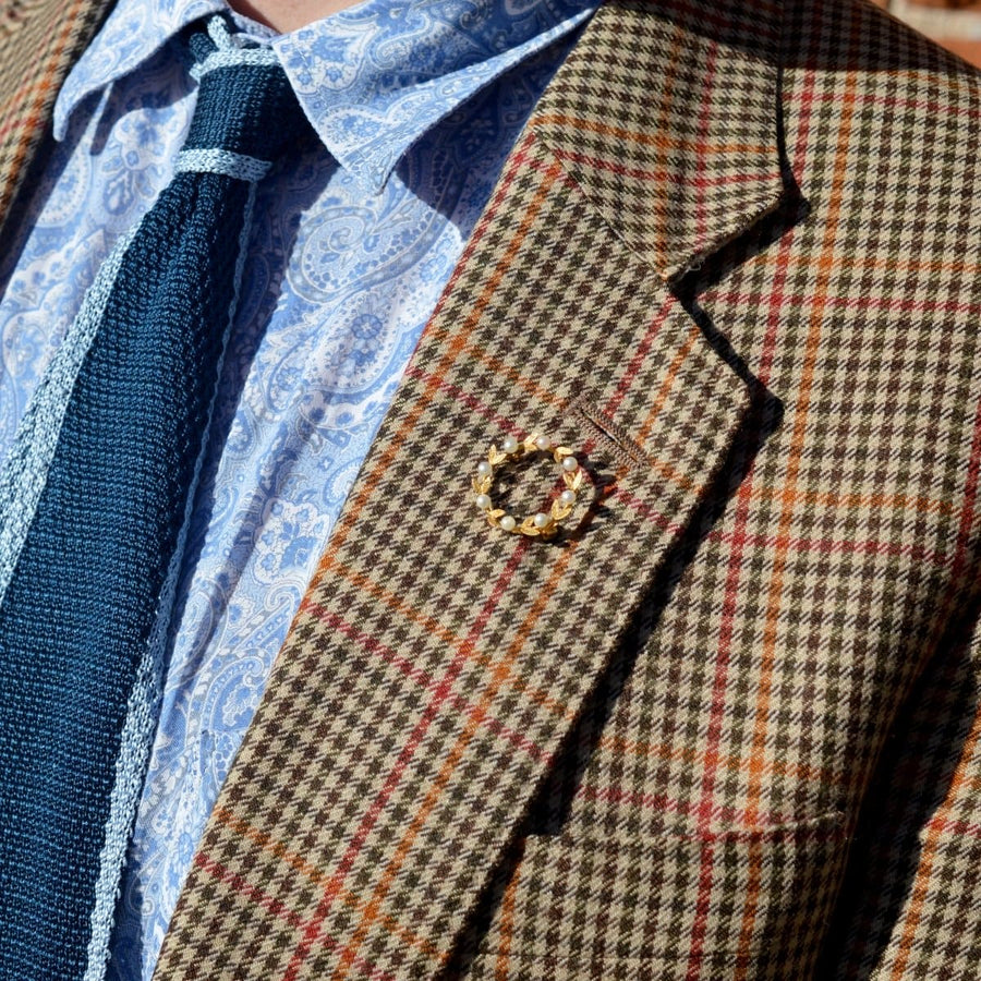 Mid 20th Century gold and cultured pearl laurel wreath brooch on a patterned blazer lapel.