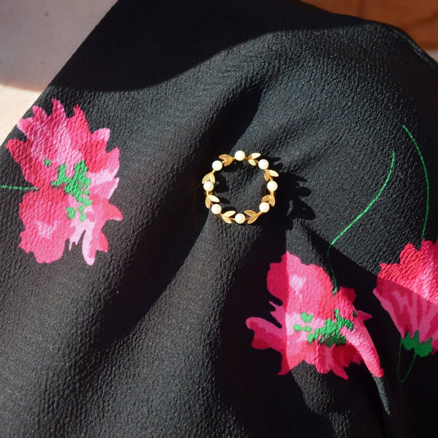 Mid 20th Century gold and cultured pearl laurel wreath brooch on floral black fabric.