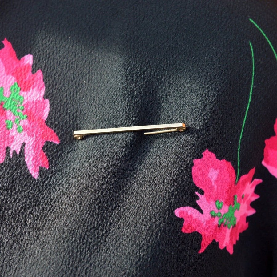 Mid Century 9ct Gold Flat Bar Brooch by Henry Griffith & Sons on a floral patterned fabric, showcasing vintage elegance.